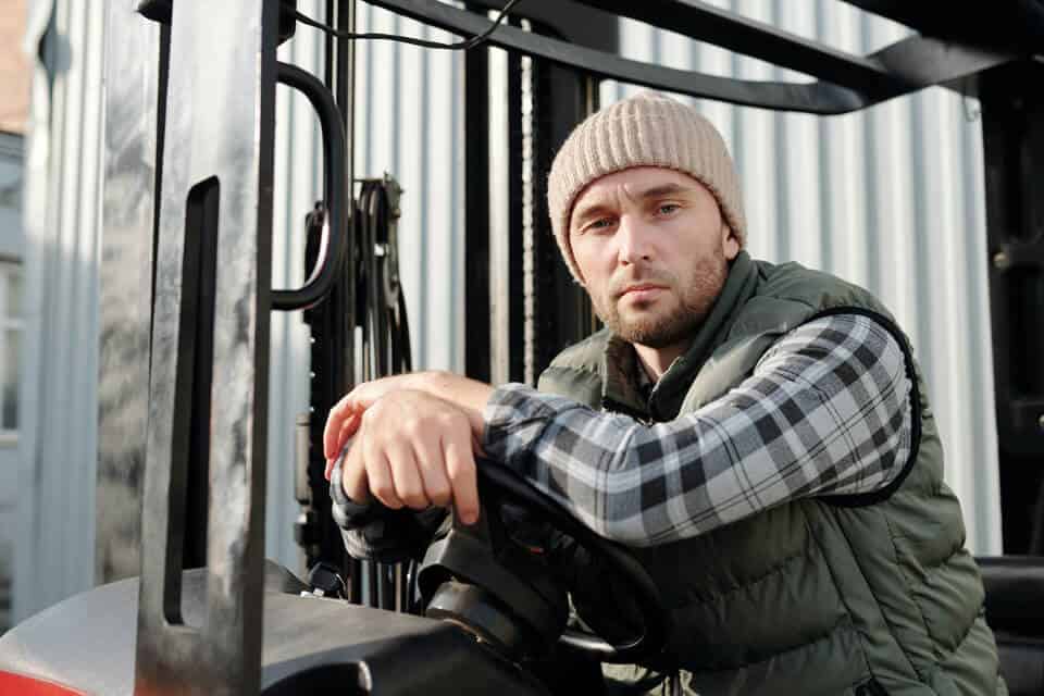 Young male student looking at camera while sitting in a forklift